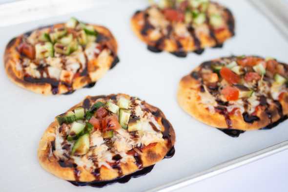four raspberry balsamic bruschetta pizzas on a baking sheet